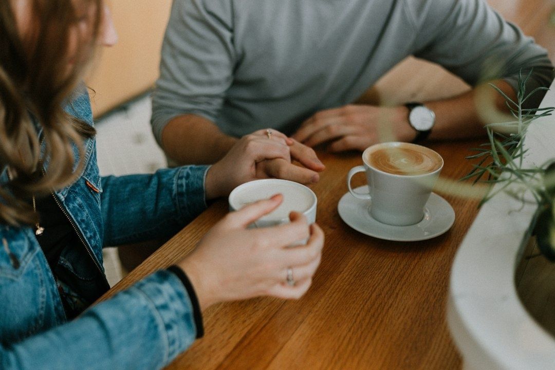 Stel houdt elkaars hand vast tijdens een gesprek bij koffie